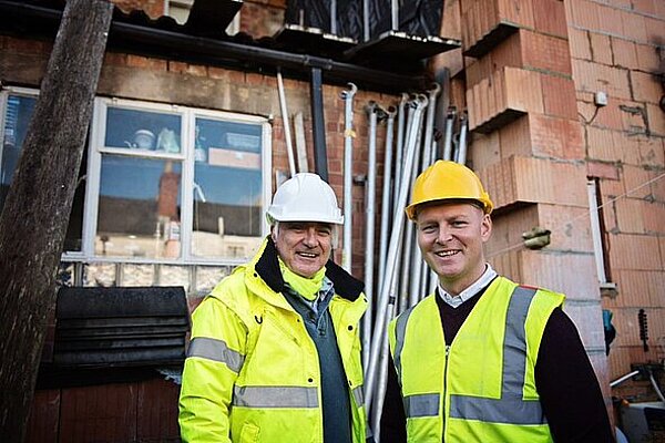 Max and Colin on a building site in hi-vis vests